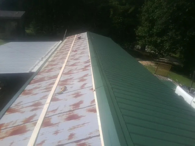 Old rusted panels beside newly installed green metal roofing — Wind Damage Roof Repair by Roofing Brothers in Saint Inigoes