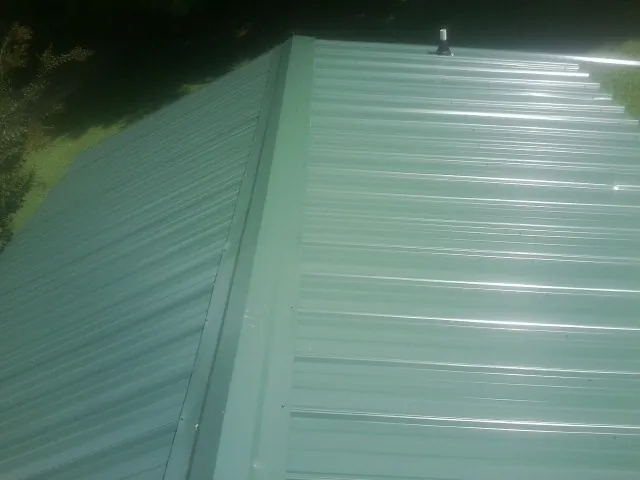 New green metal panels meeting at the ridge of a roof — Flat Roof Repair work by our crew in Saint Inigoes