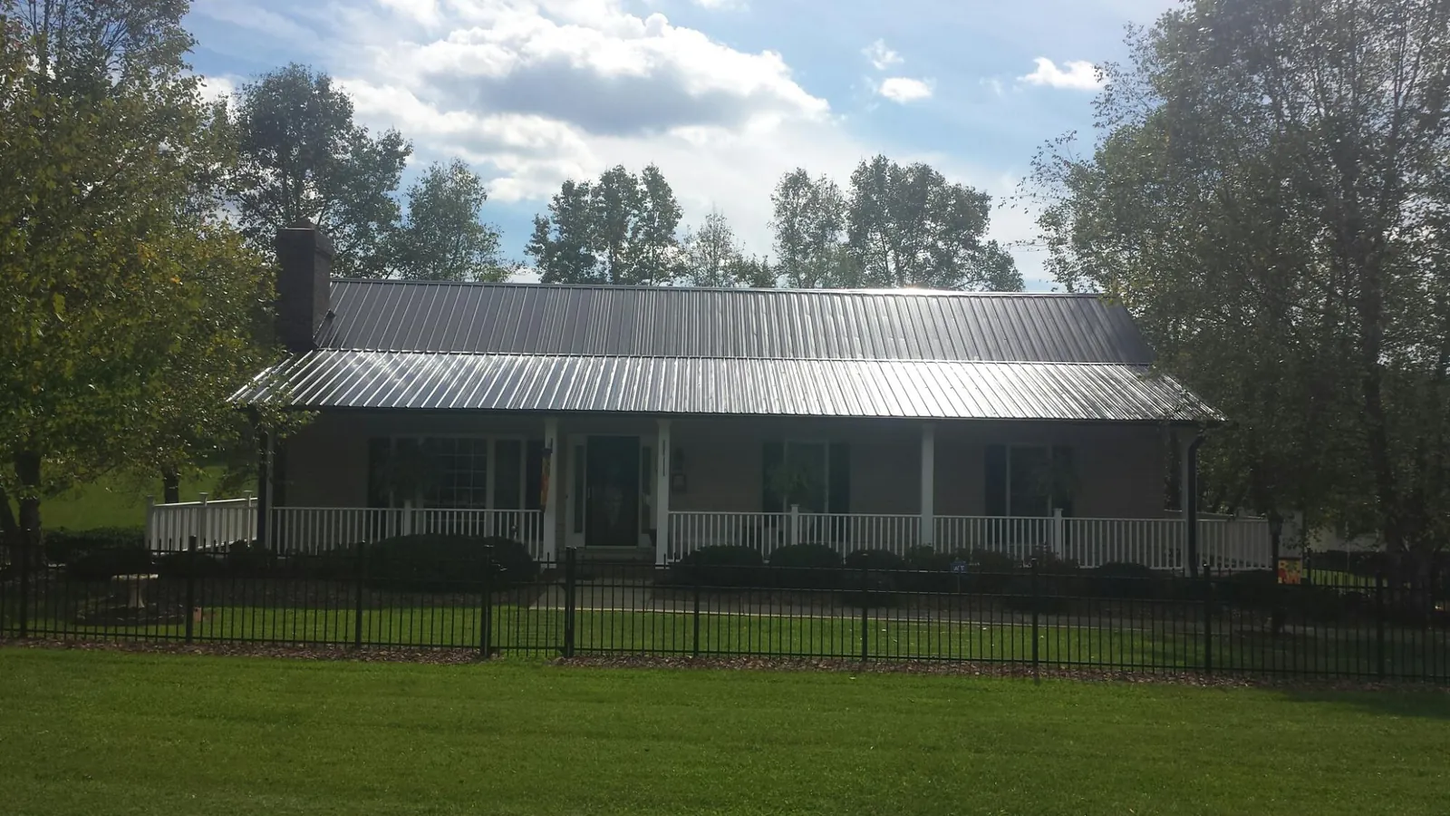 Gray metal roof on a brick ranch with a full width front porch — Gutter Guard Installation work by our crew in Saint Inigoes
