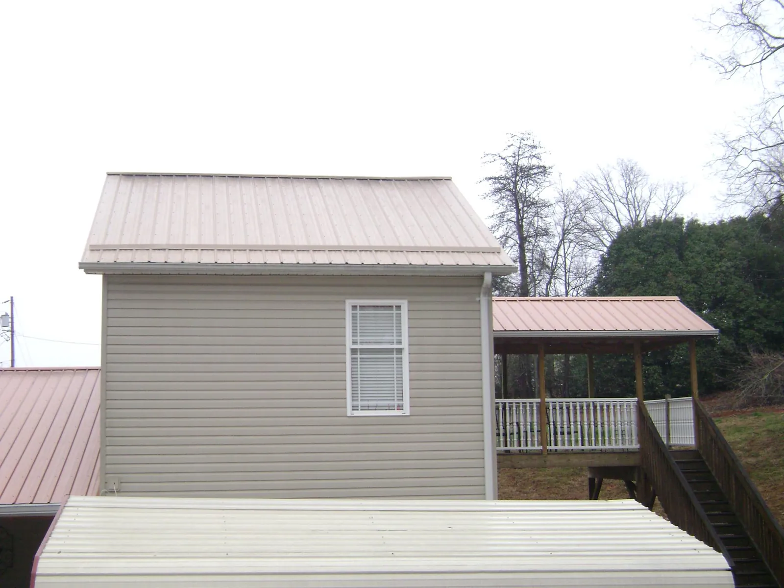 Tan metal roofs on a two story addition and attached porch, from a Roof Replacement job in Saint Inigoes