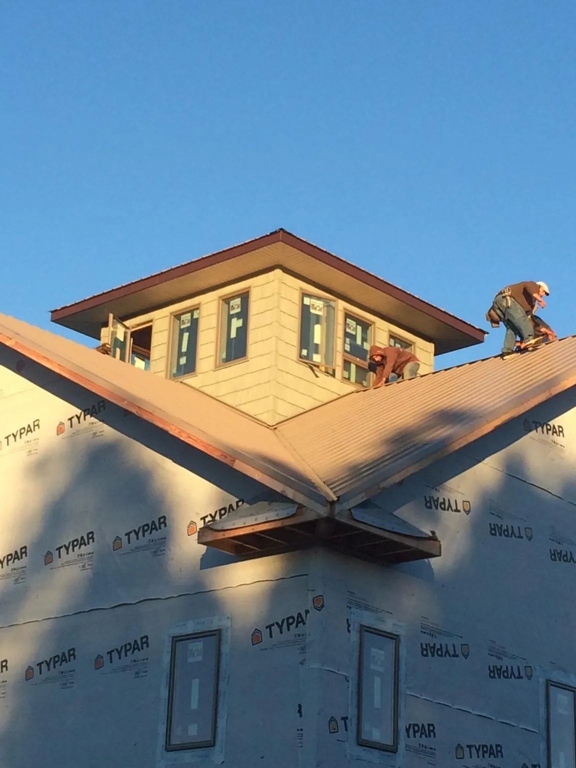 Roofers working around a rooftop cupola on a new metal roof at sunset — Roof Waterproofing in Saint Inigoes by Roofing Brothers